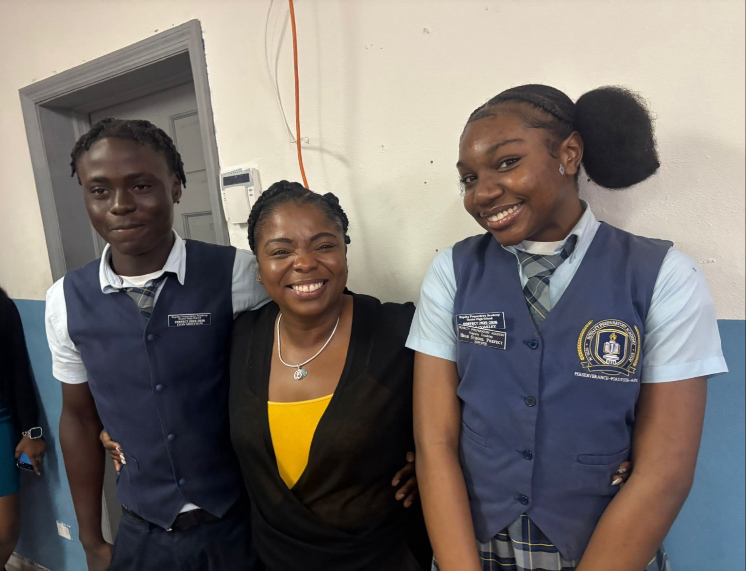 Two students in RPA uniforms standing beside a smiling adult at school.
