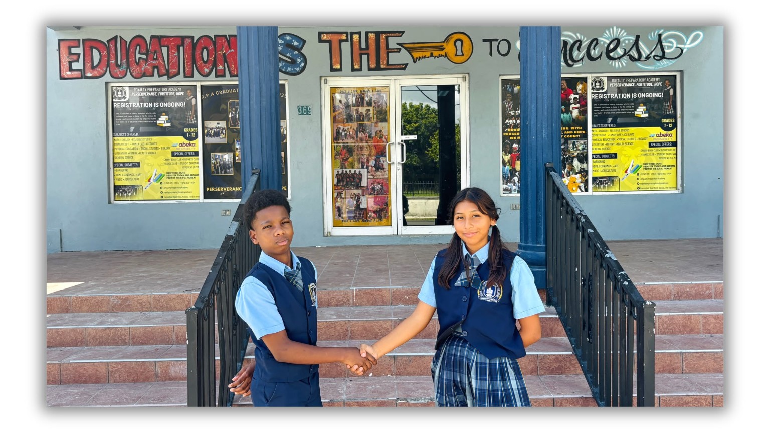 Two younger students in school uniform shaking hands at the academy entrance.